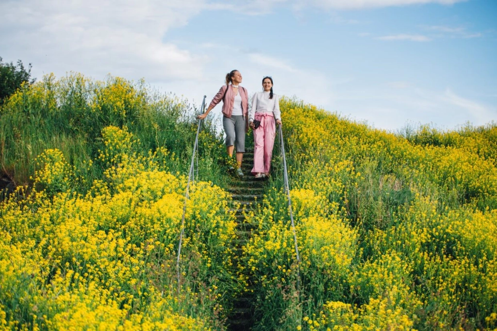 Two girls are standing in the middle of the yellow field.