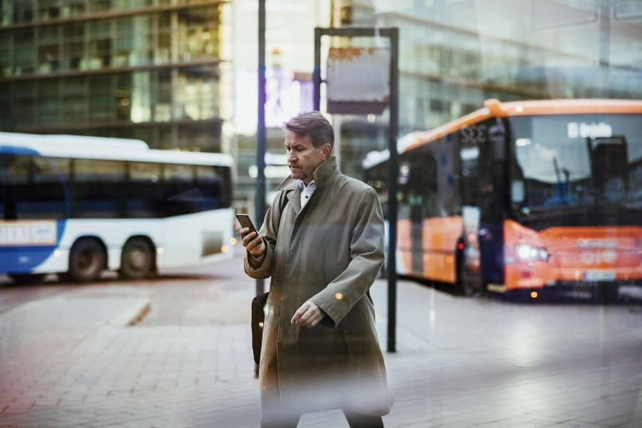 Man walks past buses and looks at his phone. - Jussi Hellsten / Helsinki Partners
