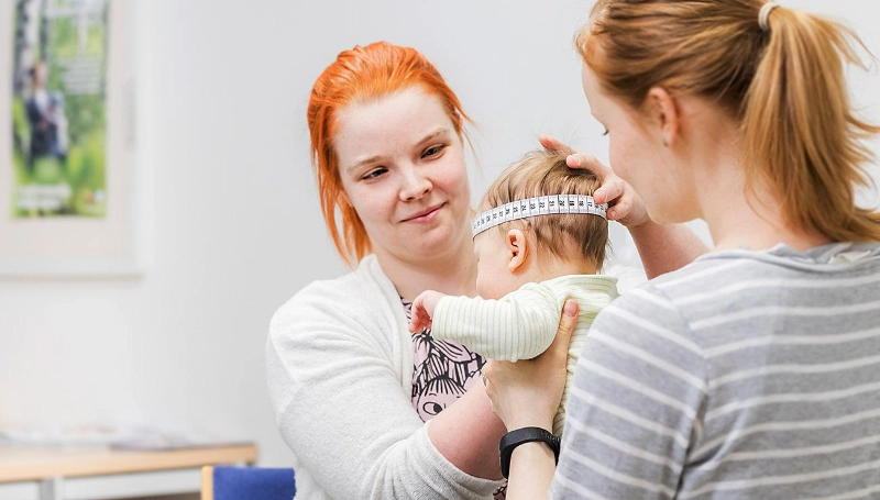 Nurse measures a child carried by their mother. - Sisä-Savon terveydenhuollon kuntayhtymä