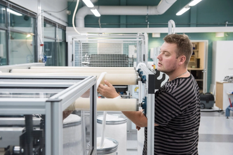 A man works in a lab that makes textiles out of wood and waste materials. - Business Finland