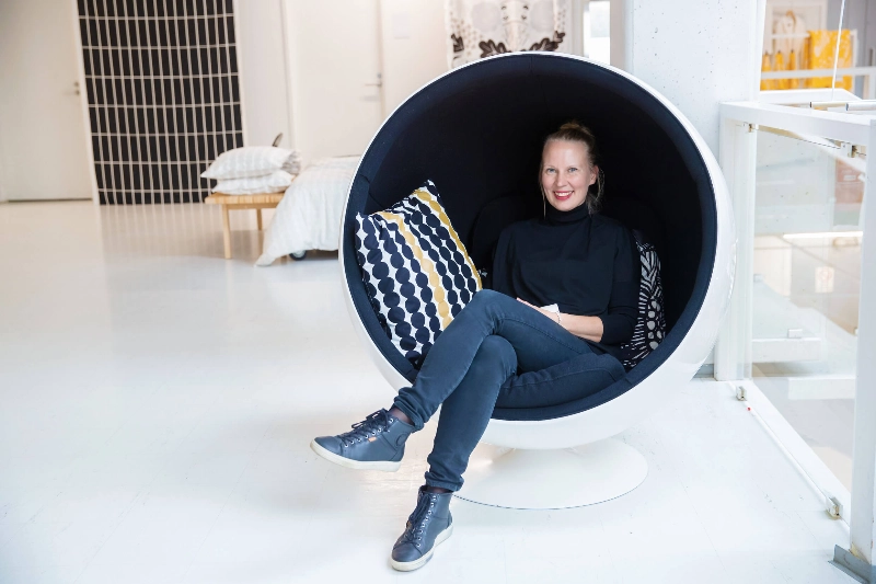 A woman wearing jeans sits inside a modern egg-shaped chair. - Yiping Feng and Ling Ouyang / Helsinki Partners