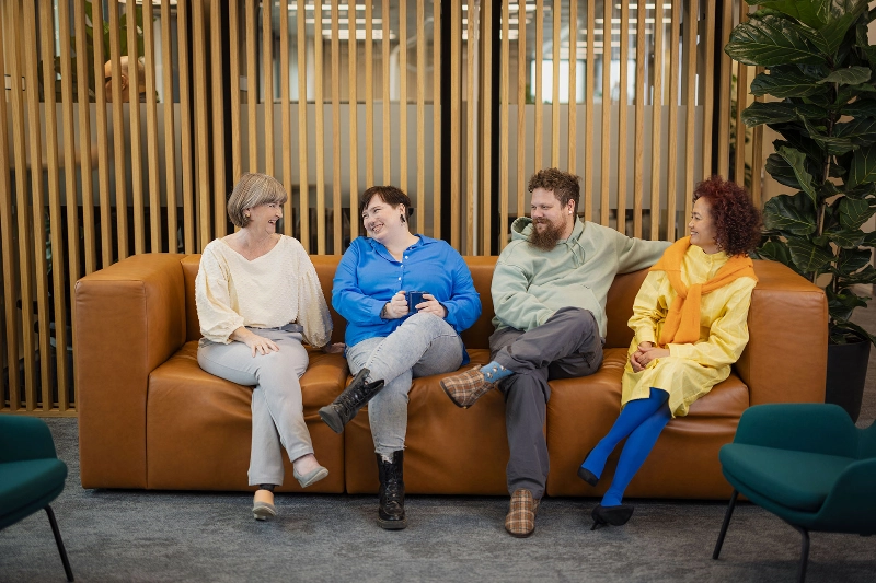 Four people sitting on a sofa talking